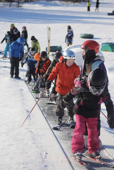 Image-22 Young beginner skiers going up the ski escalator